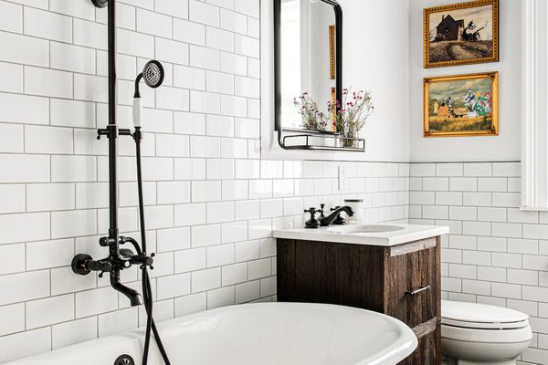 铸铁浴缸在全白地铁瓷砖浴室。