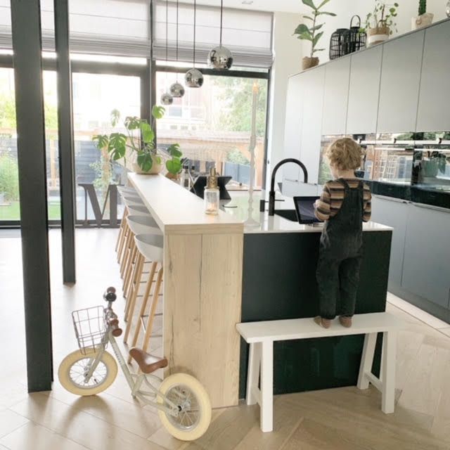 在厨房里，一个蹒跚学步的男孩紧挨着一辆小自行车。