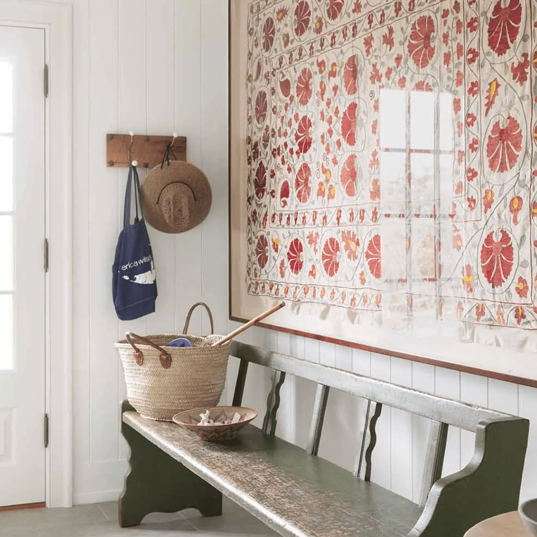 门廊上装饰着一条古色古香的木凳和一床镶框的大被子