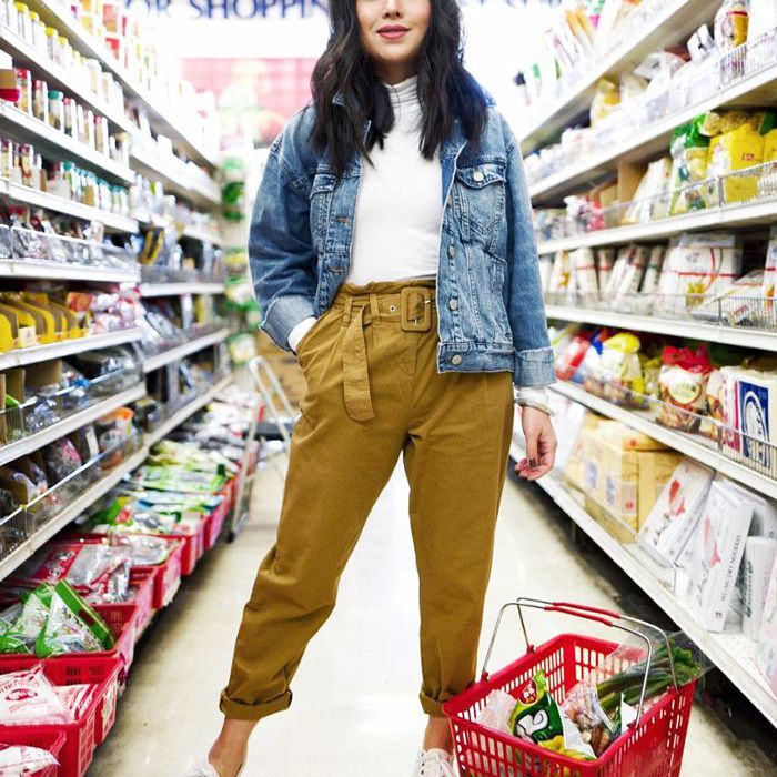 年轻女子站在在她的脚下购物通道，全红购物篮中