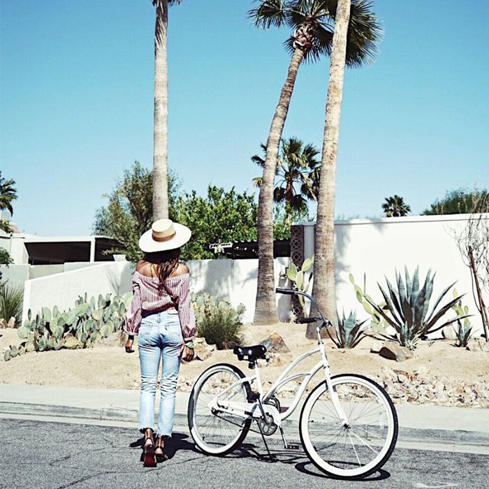 在一顶帽子一个女人从背后在夏日的阳光下站在旁边的自行车见过。