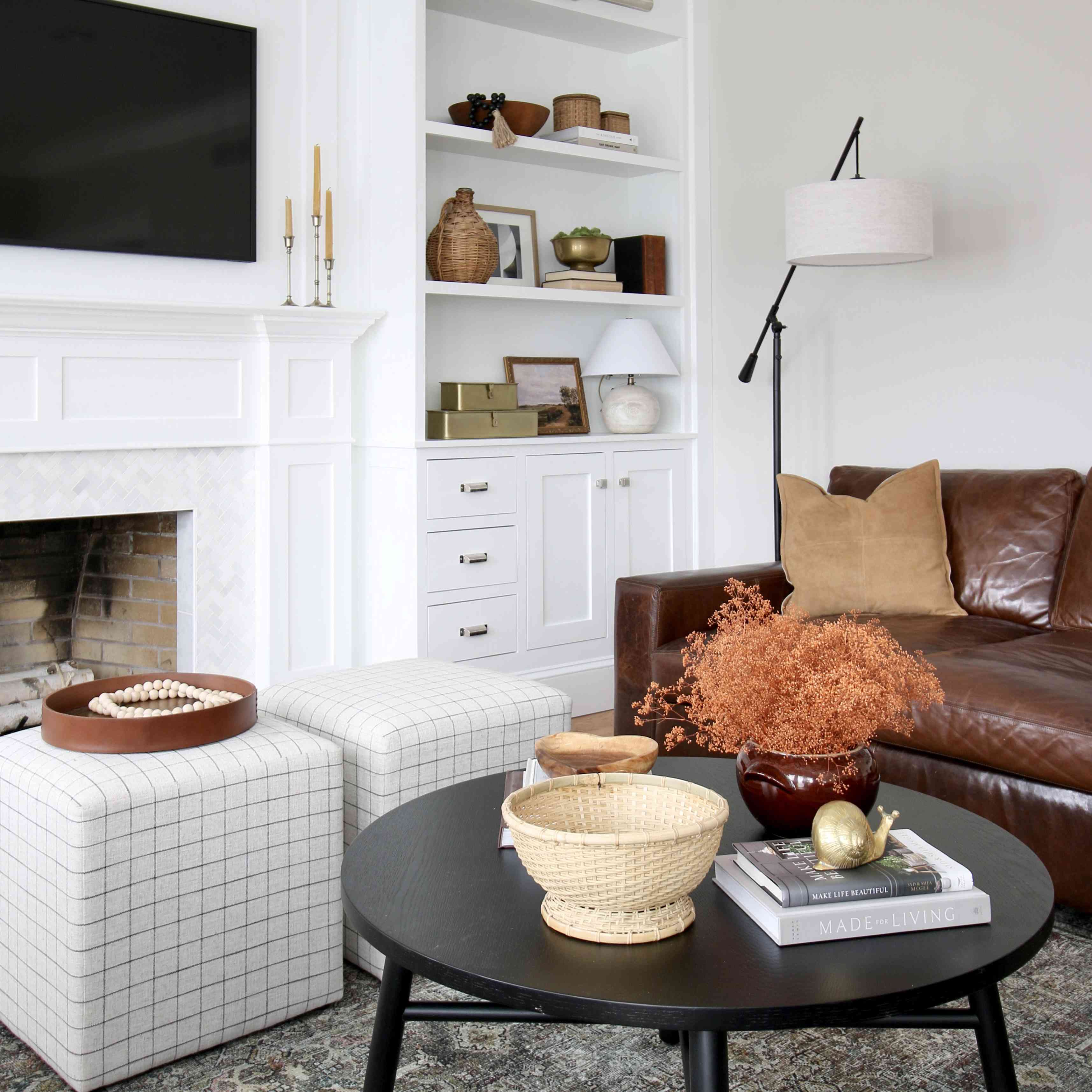 客厅里有一张黑色的桌子，两个脚垫和棕色的皮沙发。