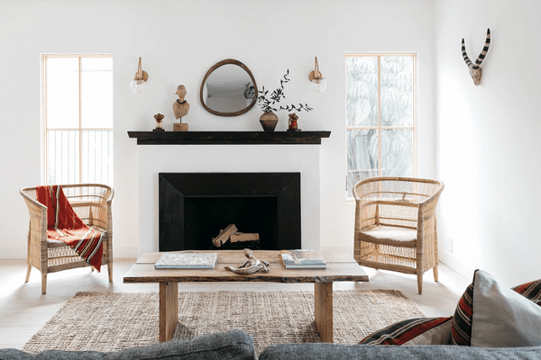 一个带壁炉，一张木桌和两个藤椅的起居室