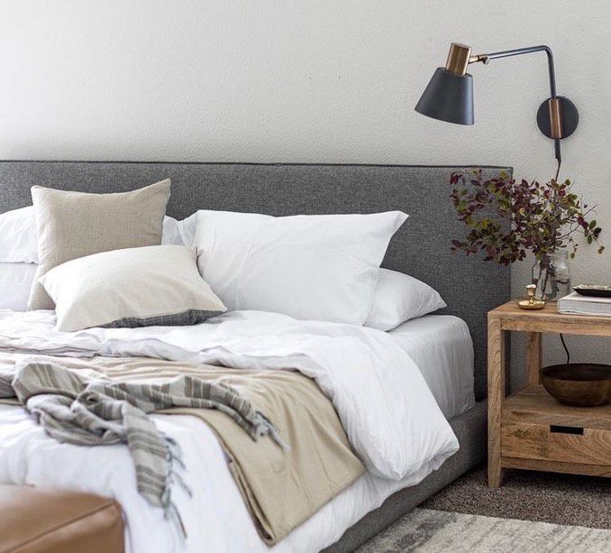 凌乱的床，白色的被子和灰色的床头板。