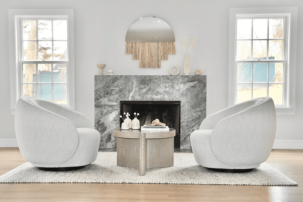 宽敞的客厅里有一座灰色的大理石壁炉和两把圆形椅子