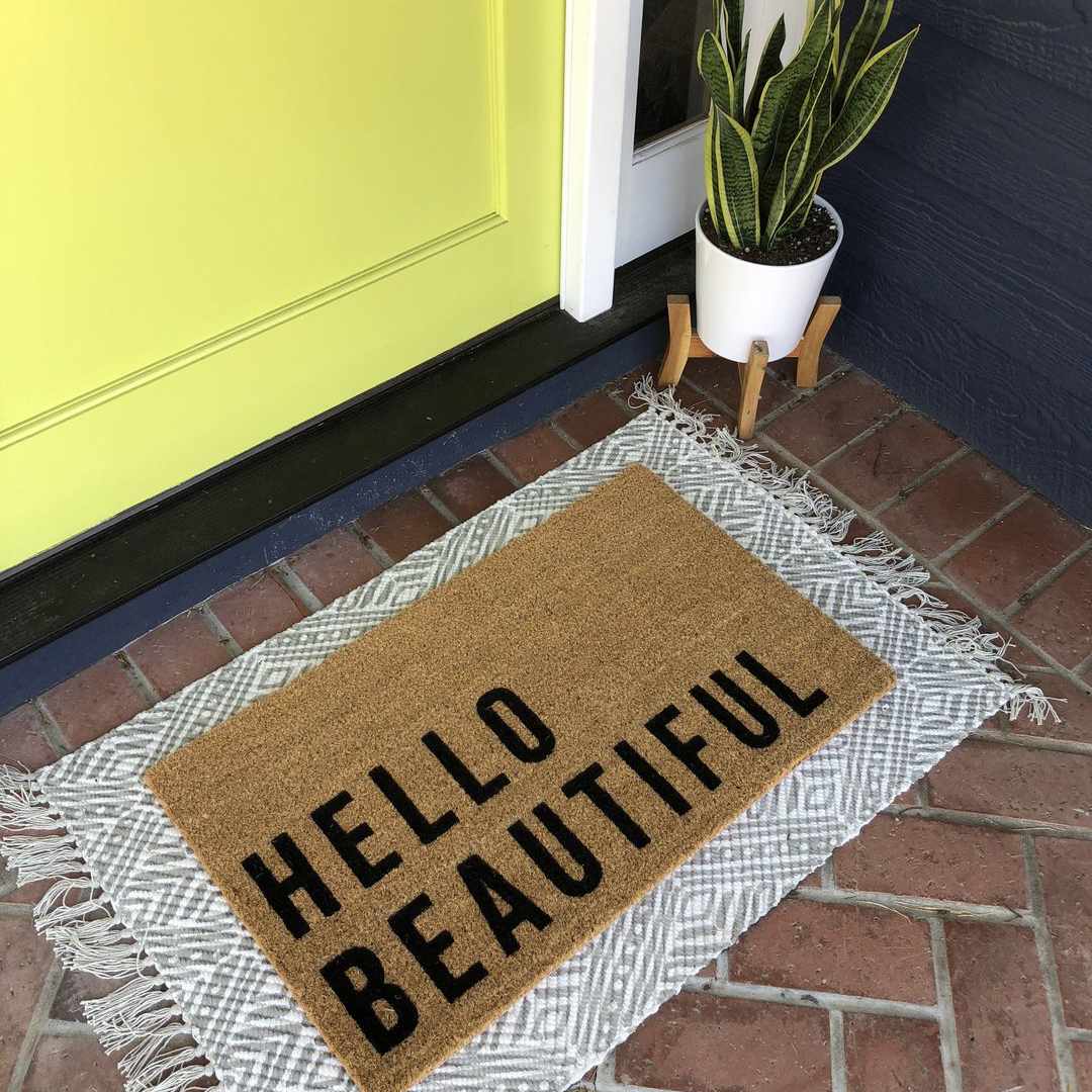 您好在黄色门前面的美丽的门垫。