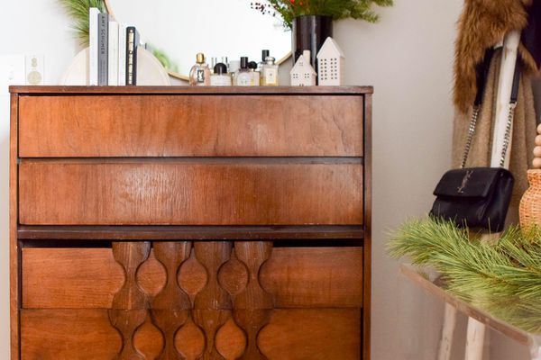 round mirror with attached garland sitting on top of a dresser