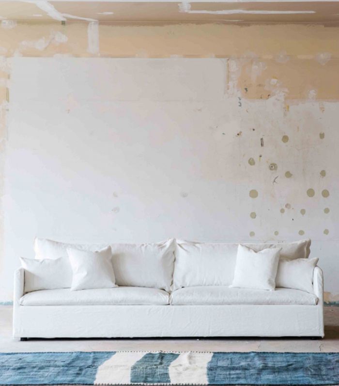 白色亚麻四人座沙发，靠枕松垮。