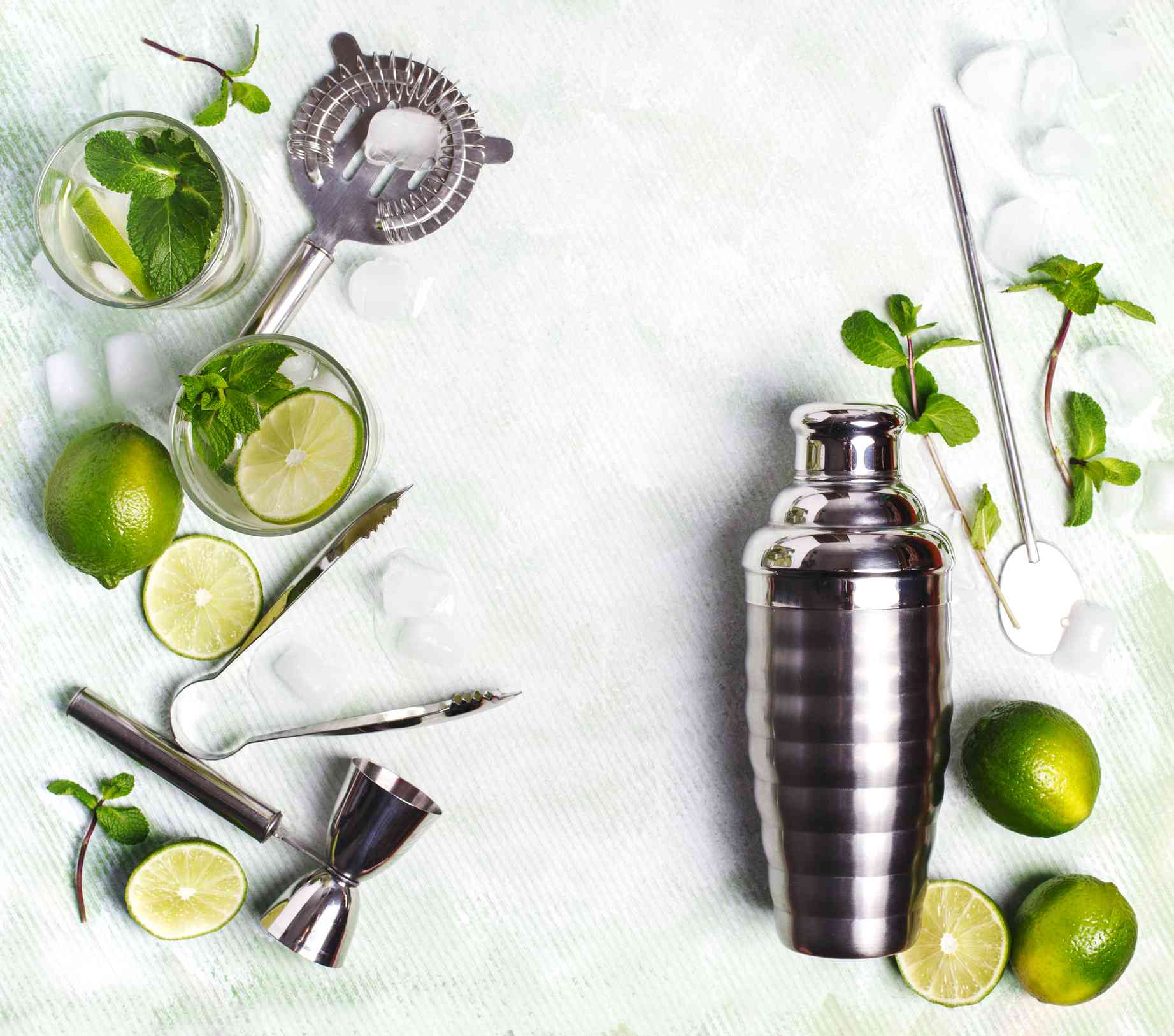 鸡尾酒调酒器周围的酸橙和酒吧工具。