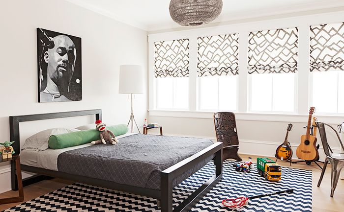 一间卧室混合版画和时间段，并设有吉他和玩具散落有关图案的地毯