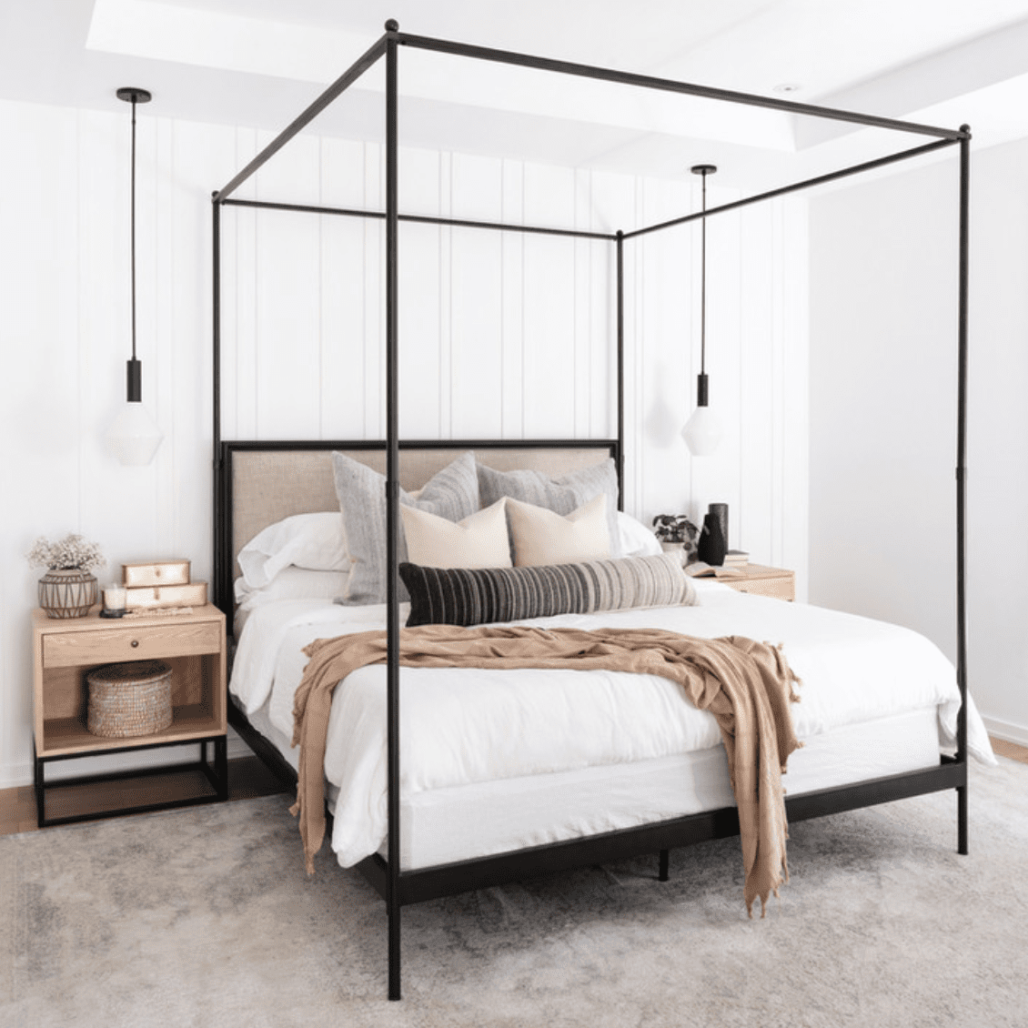 一间带黑色金属床，白色床单和米色的卧室扔枕头和毯子