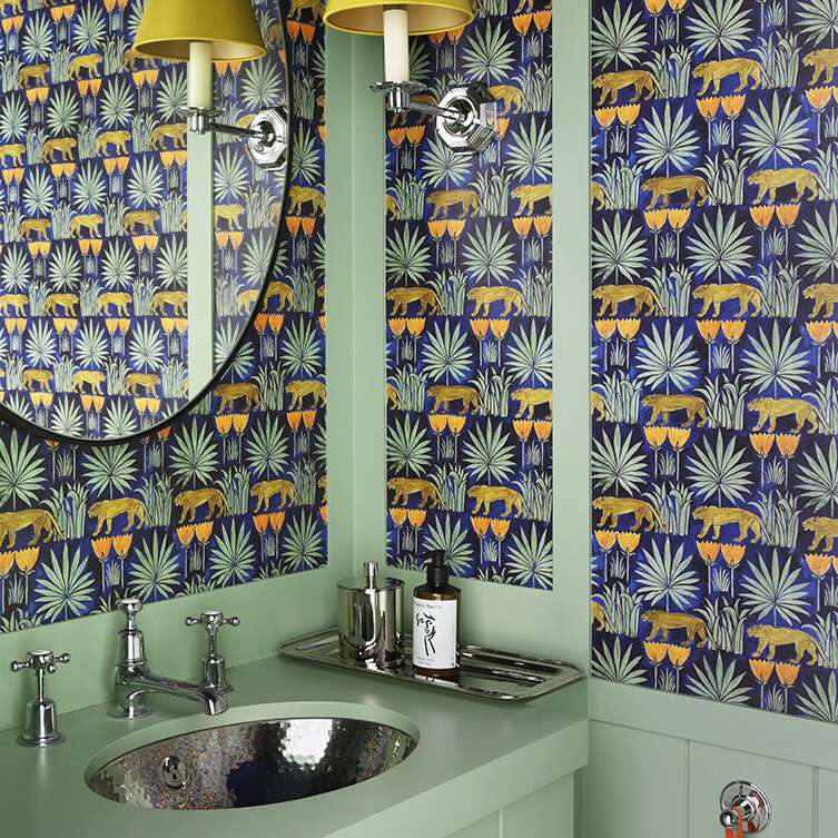 一个充满活力的化妆室，绿色的橱柜，醒目的墙纸和黄色的灯