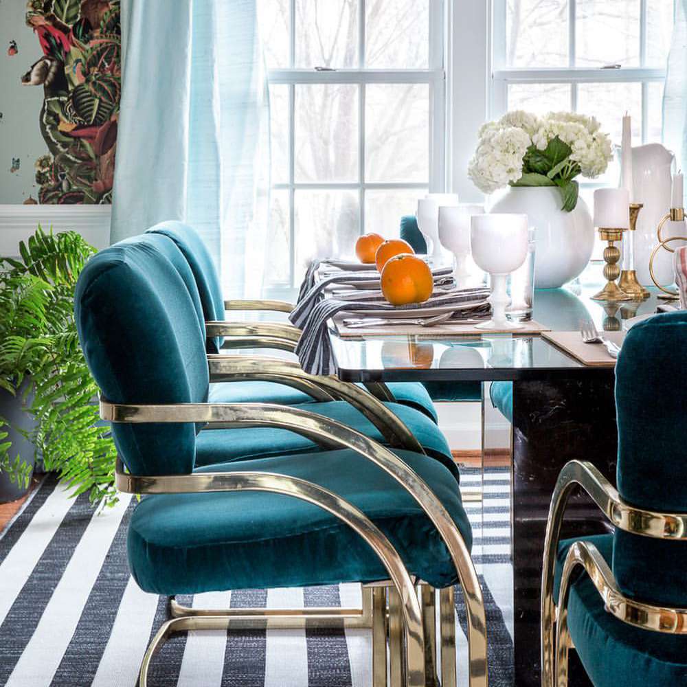 复古的餐桌与蓝绿色天鹅绒椅子。