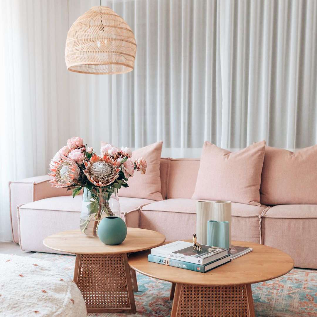 咖啡桌旁边的粉色沙发上放着人造花束。